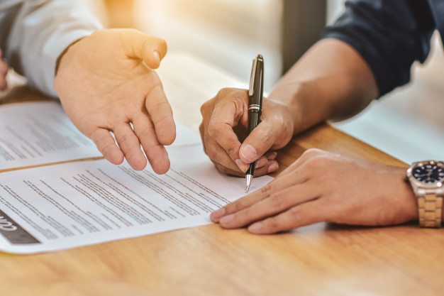 close-up-hand-holding-pen-sign-contract-document_10541-1024